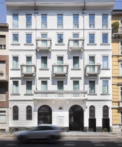a car driving past a large white building at Senato Hotel Milano in Milan