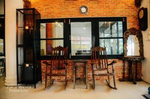 two chairs and a table in front of a brick wall at Chinawat Hotel in Sukhothai