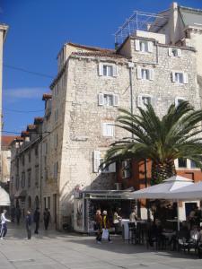a large building with a palm tree in front of it at Hotel Kastel 1700 in Split