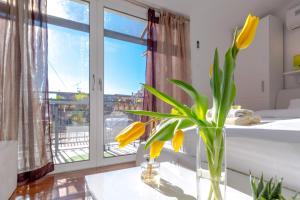 a vase with yellow flowers on a table in front of a window at Apartments and Rooms Villa Erede in Split