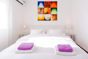Una cama blanca con dos almohadas moradas. en Apartments and Rooms Villa Erede, en Split