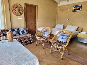 een kamer met een bed en twee stoelen en een bank bij Basanti Rawat Homestay in Munsyari