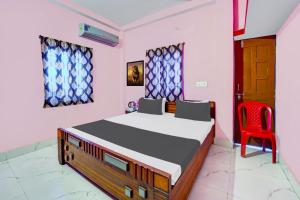 Un dormitorio con una cama y una silla roja. en Hotel O S Hotel & Restaurant, en Patna