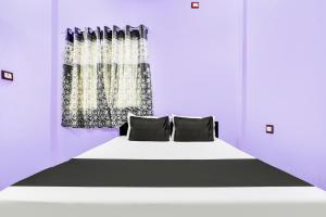 a bedroom with a white bed with black pillows at Hotel O Sai Sarkar Inn in Rāipur