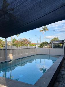 a swimming pool with a fence and palm trees at Tropical Ground-Floor Retreat Cairns in Cairns North