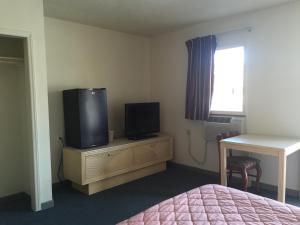 1 dormitorio con 1 cama, TV y escritorio en Coastal Motel en Jacksonville