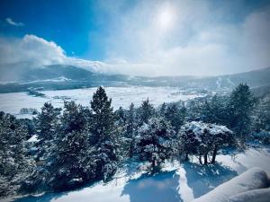 ein schneebedeckter Berg mit Bäumen und der Sonne am Himmel in der Unterkunft Chalet Chaleureux avec Jacuzzi et Parking - FR-1-593-121 in Les Angles
