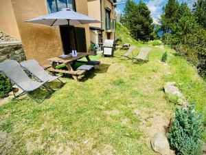 un tavolo da picnic e sedie con un ombrellone sull'erba di Chalet chaleureux avec jacuzzi, parking et Wi-Fi aux Angles - FR-1-593-121 a Les Angles