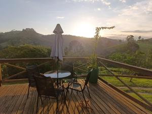 a table and chairs on a wooden deck with a view at Solar dos Pinhais in Santo Antônio do Pinhal