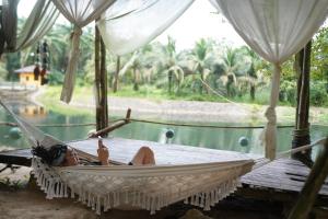 a woman laying in a hammock by a pool at KRABI BAMBOO KINGDOM at AOLUEK PARADISE in Ao Luk