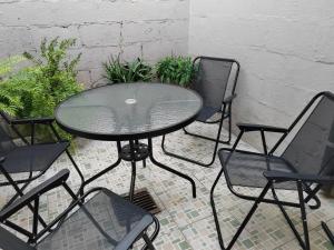 a glass table and four chairs on a patio at Hostal La Campana in San Miguel