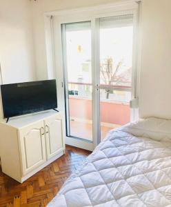 a bedroom with a bed and a flat screen tv at Cantinho de Algés in Algés