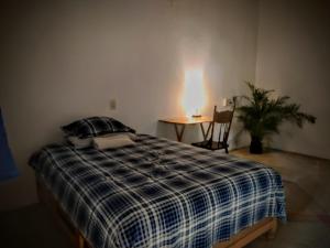 a bedroom with a bed and a table with a plant at Casa pájaros- Habitacion Quetzal in Troncones