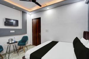 a bedroom with a bed and two chairs and a tv at Hotel O The smart haven in Ghaziabad