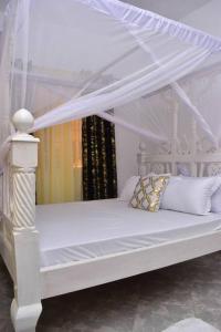 a white bed with a canopy in a room at Taji Two bedroom lovely apartment in Malindi