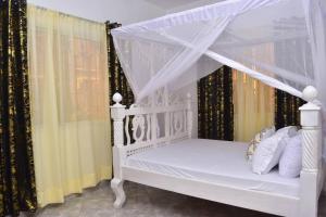 a white bed with a canopy in a room at Taji Two bedroom lovely apartment in Malindi