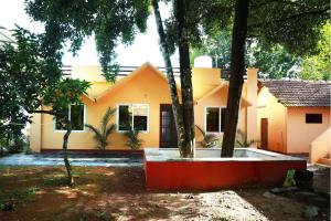 a yellow house with trees in front of it at Back Packers Cochin Villa in Cochin