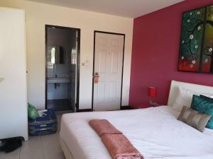 a bedroom with a white bed with a red wall at Standard Room in Kata Beach