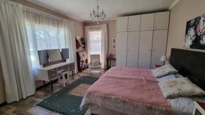 a bedroom with a bed and a desk and a television at Bird Song in Cape Town
