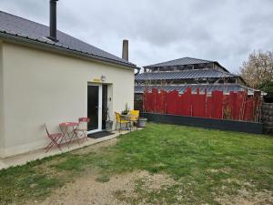a backyard with a red fence and a table and chairs at La salle de jeux in Saint-Lubin-en-Vergonnois