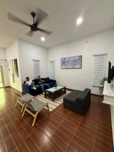two people sitting on a couch in a living room at Bagan Serai Simpang Empat Parit Buntar Perak by 3SIBS in Bagan Serai