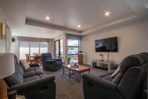 a living room with two couches and a tv at Comfort, quality, great location in Hamilton