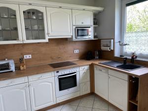 a white kitchen with white cabinets and a sink at Ferienhaus Amare mit Fasssauna, eigener Terrasse & Kamin in Bautzen