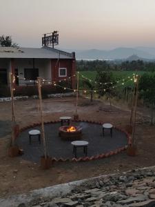 a fire pit with benches and lights in front of a house at Hotel Ekant tourist resort in Junnar