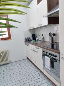 a kitchen with white cabinets and a stove top oven at Rooftop Apartments - Gemütliches Apartment 4P nahe Ratiopharm Arena in Neu Ulm