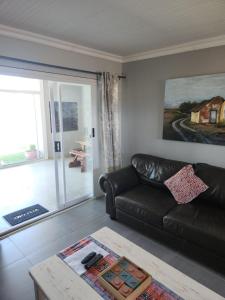 a living room with a leather couch and a table at Volgenoeg Self Catering Cottage in Oudtshoorn