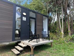 a black tiny house with two chairs on a bench at The Dacious by Tiny Away in Midgenoo