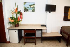 Habitación con escritorio con silla y TV. en Hotel Puerto Ballesta en Tonsupa