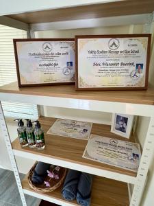 a shelf with certificates and bottles of medicine at BSK Bungalows in Lipa Noi
