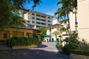 a street in front of a building with palm trees at Apartotel & Suites Villas del Rio in San José