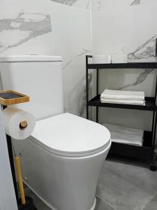 La salle de bains est pourvue de toilettes blanches et d'une étagère avec des serviettes. dans l'établissement Smart Suite, à Madrid