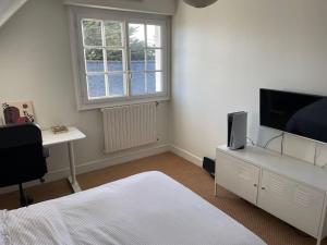a bedroom with a bed and a flat screen tv at La Sinagote in Séné