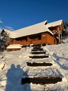 a snow covered building with stairs in front of it at Приватна садиба ''Світлиця гуцульщини" in Vorokhta