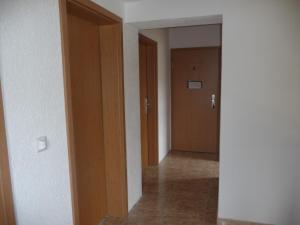 pasillo vacío con 2 puertas y suelo de baldosa en Pension Andrea, en Lugau