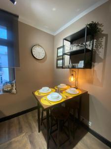 a dining room table with plates and a clock on the wall at Polonia Apartments No-68 Near Piotrkowska in Łódź +33 photos