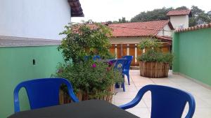 a patio with blue chairs and a table and flowers at Pouso D' Braga in Pirenópolis