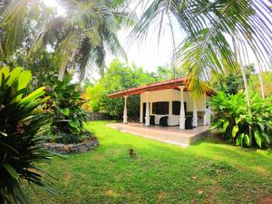 a small house with a green yard in front of it at Dambullawatha Bungalow Garden Villa in Hikkaduwa