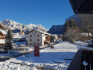 een dorp bedekt met sneeuw met bergen op de achtergrond bij La Casa del Mulino in Pozza di Fassa