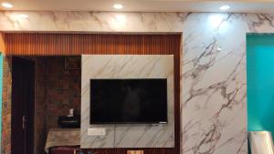TV de pantalla plana en una pared de mármol en AK Royal Guest House Service Greater Noida West, en Greater Noida