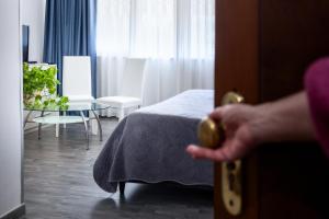 a person opening a door to a bedroom with a bed at Hotel Giulietta e Romeo in Casal Palocco