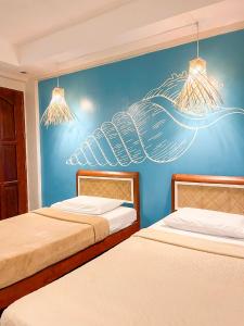 twee bedden in een kamer met een blauwe muur bij Amos Portside Inn El Nido in El Nido