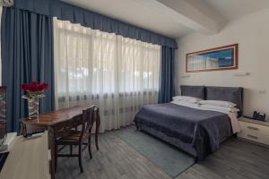 a bedroom with a bed and a table and a desk at Hotel Giulietta e Romeo in Casal Palocco