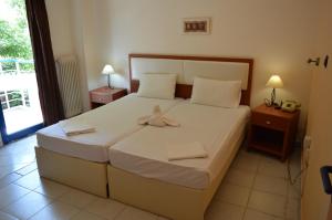 a bedroom with a large bed with two towels on it at Hotel Eleni in Paralia Dionysiou