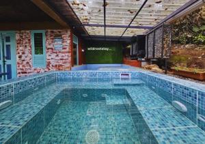 - une piscine intérieure revêtue de carrelage bleu dans l'établissement Wild root stay- Orchid Chalet, à Vythiri
