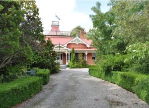 a large red house with a driveway in front of it at Ormiston House in Strahan