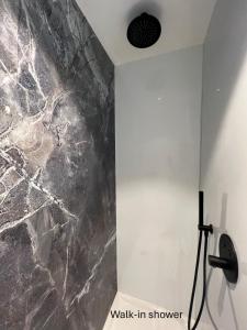 a walk in shower with a black marble wall at Appartement ‘W Vacantia’ in De Haan +9 photos